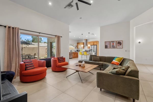 Bright open living room with colorful seating, kitchen beyond, and sliding doors to a patio